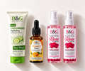 Four B&G Black & Gold skincare products arranged side by side on a white background: a green and white Cucumber Face Wash tube, an amber Vitamin C Serum dropper bottle, and two pink Rose Water spray bottles.